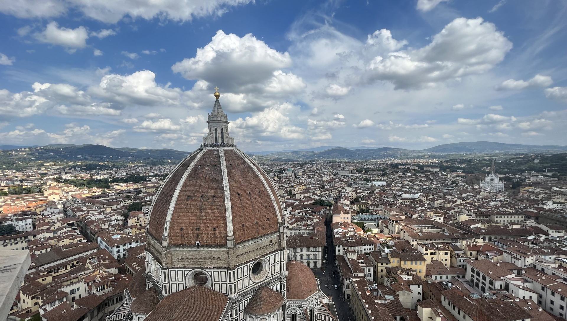 A panoramic view over Florence's terracotta rooftops and the Duomo under a bright sky